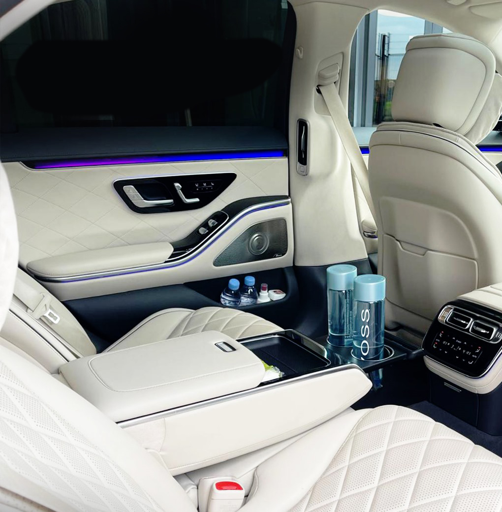 The cognac diamond-quilted leather interior of a Mercedes S-Class, with rear armrest controls and the portrait dashboard screen.